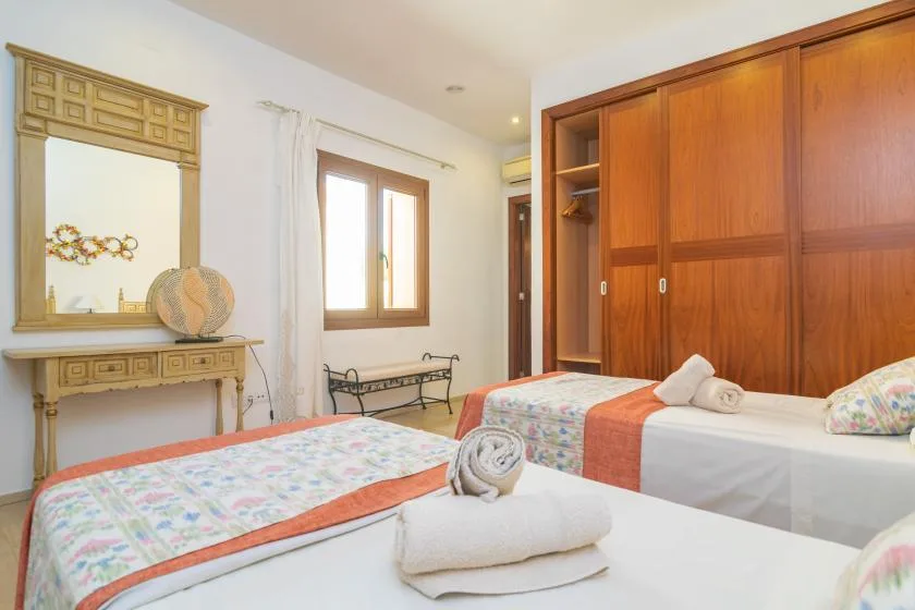 Un dormitorio con dos camas, un armario de madera y una ventana.