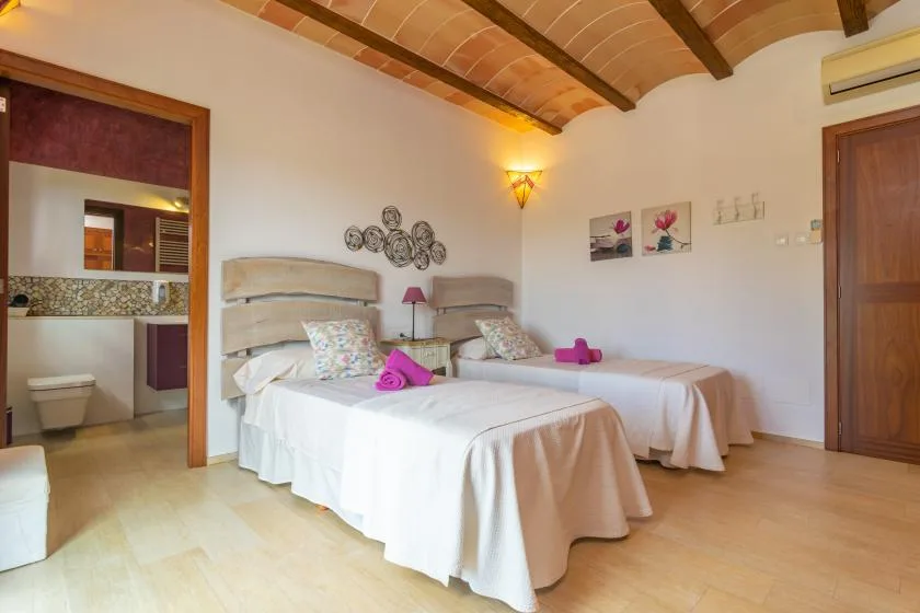 Un dormitorio con dos camas, ropa de cama clara y un techo curvo de madera.