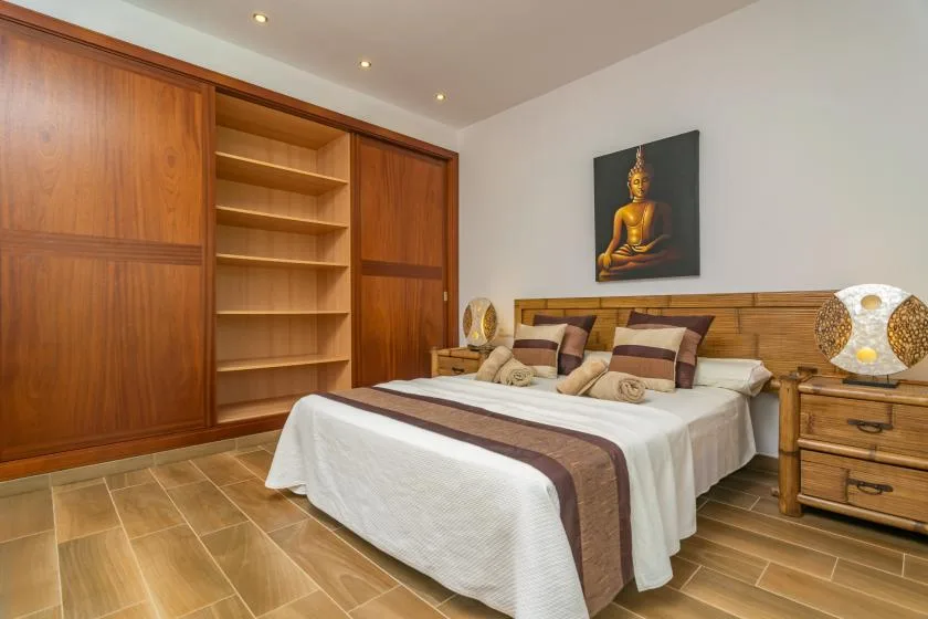 Un dormitorio con una cama bien hecha y estanterías de madera empotradas.
