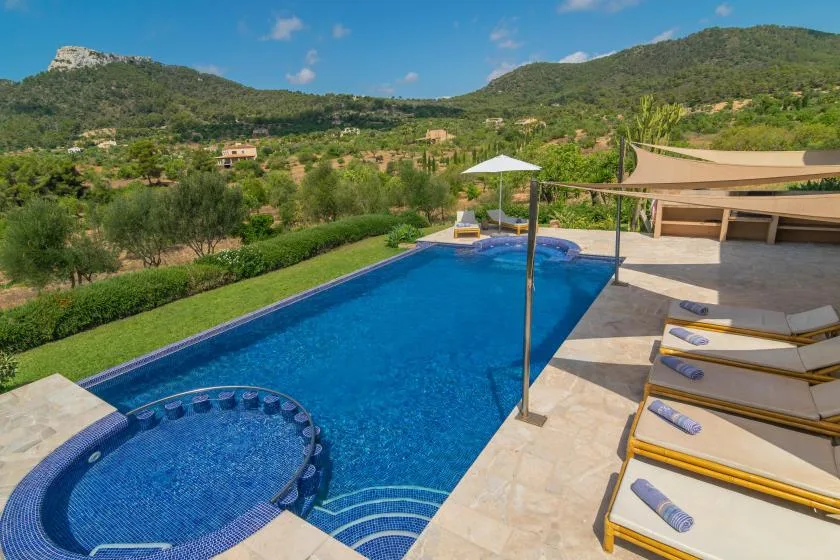 Una piscina al aire libre con un spa circular junto a varias tumbonas.