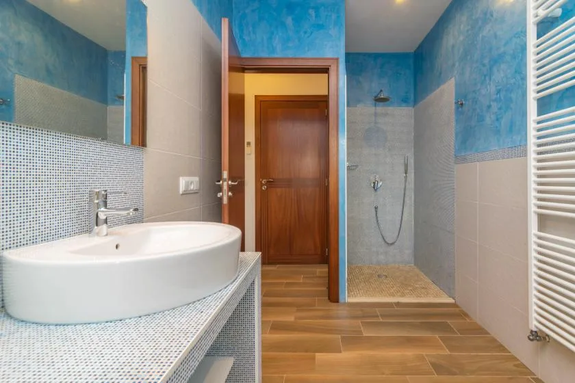 Un baño con lavabo, superficies alicatadas y una zona de ducha.