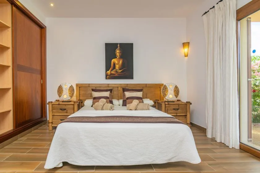 Un dormitorio con una cama bien hecha y una imagen enmarcada de Buda sobre el cabecero.