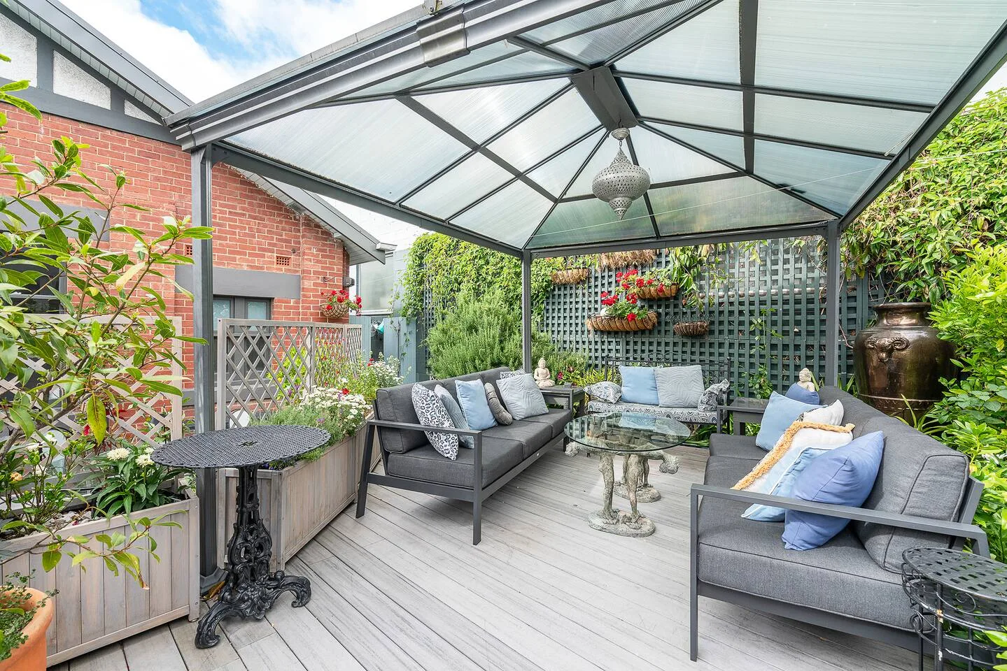 Una zona de estar exterior cubierta con muebles acolchados y plantas en macetas.