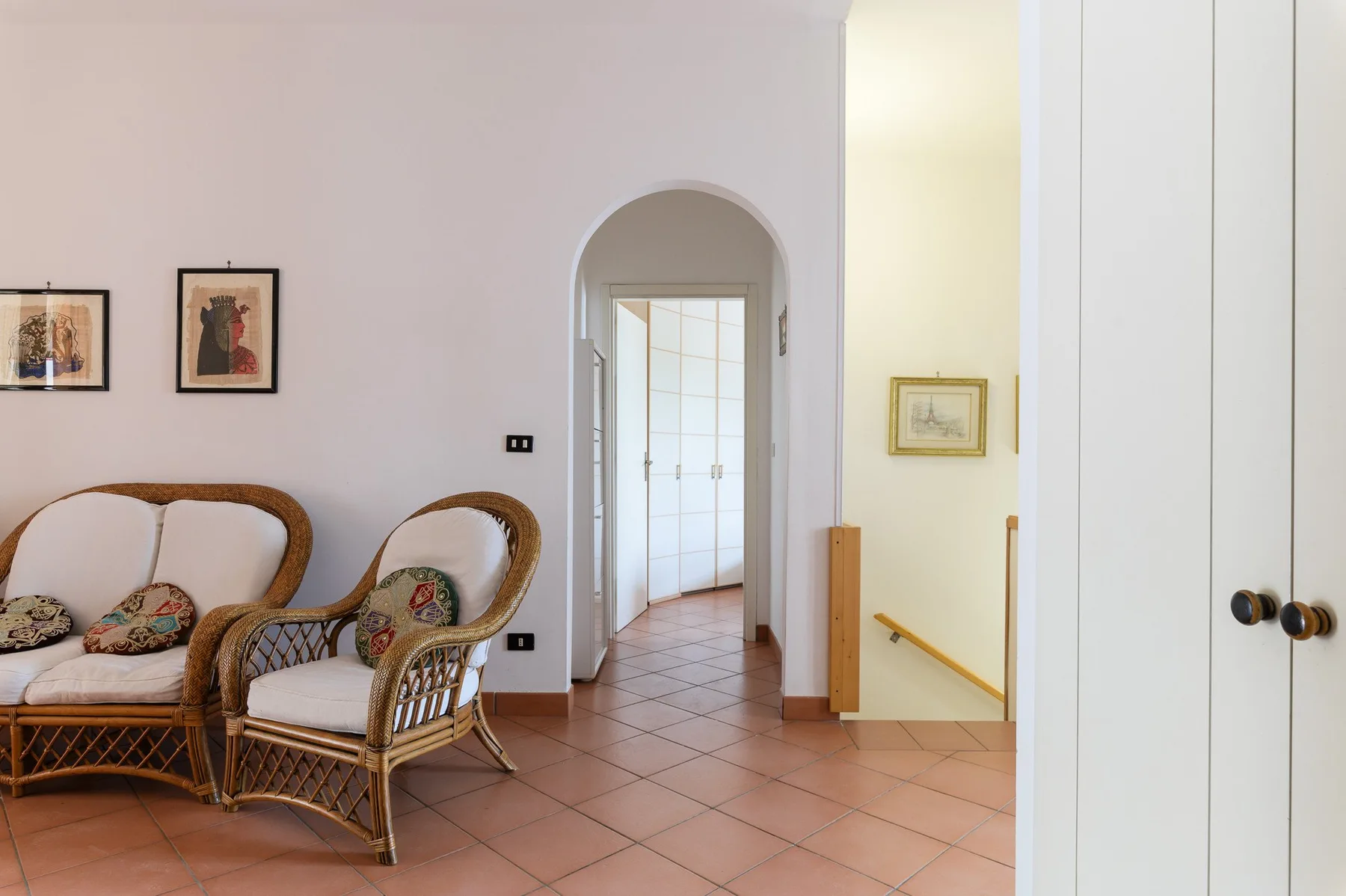 A sitting area with wicker seating beside an arched doorway.