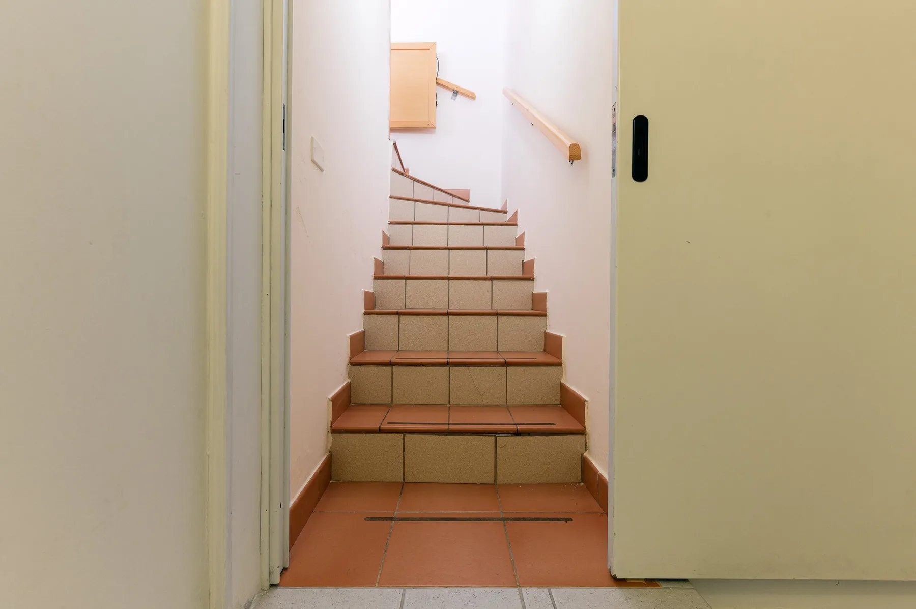A tiled staircase with wooden handrails is visible through an open doorway.