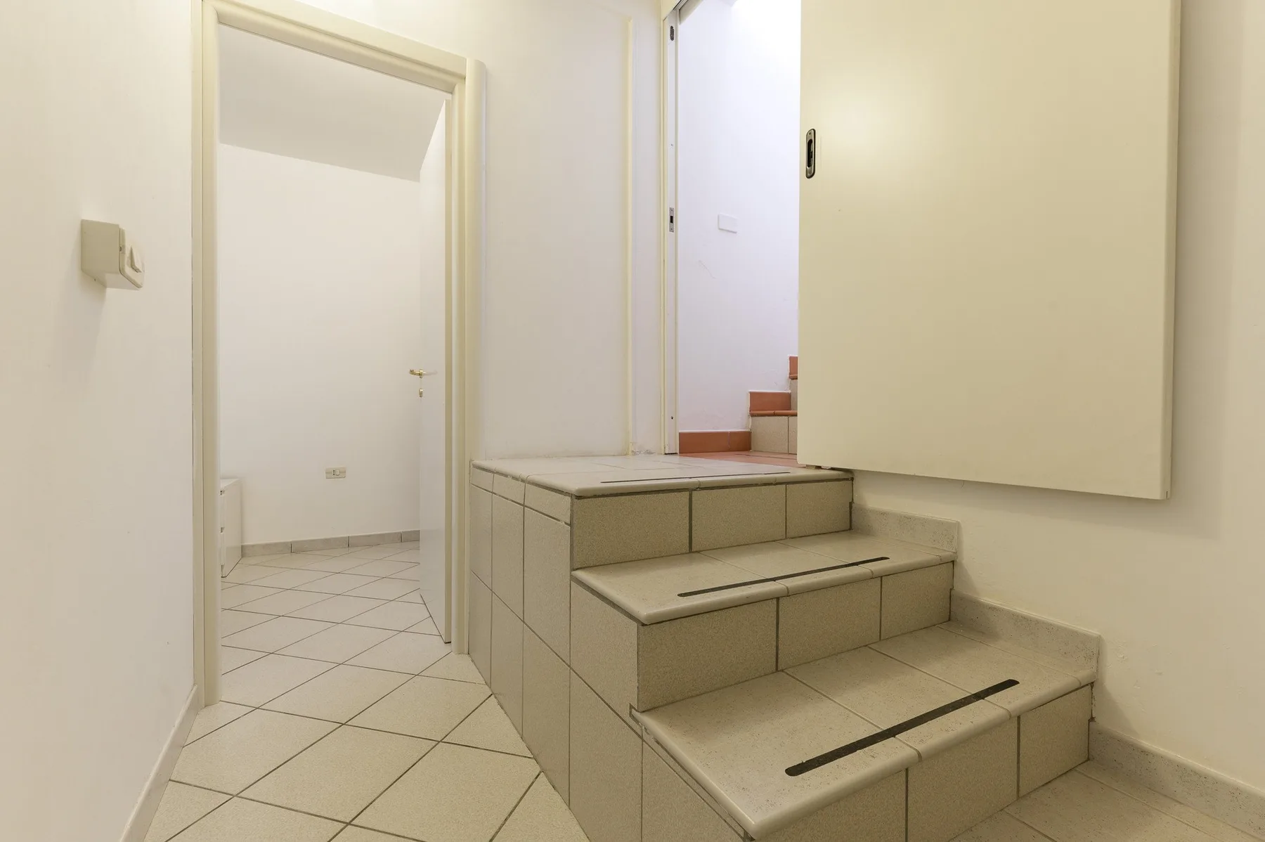 A tiled interior stairway leads to an open doorway.