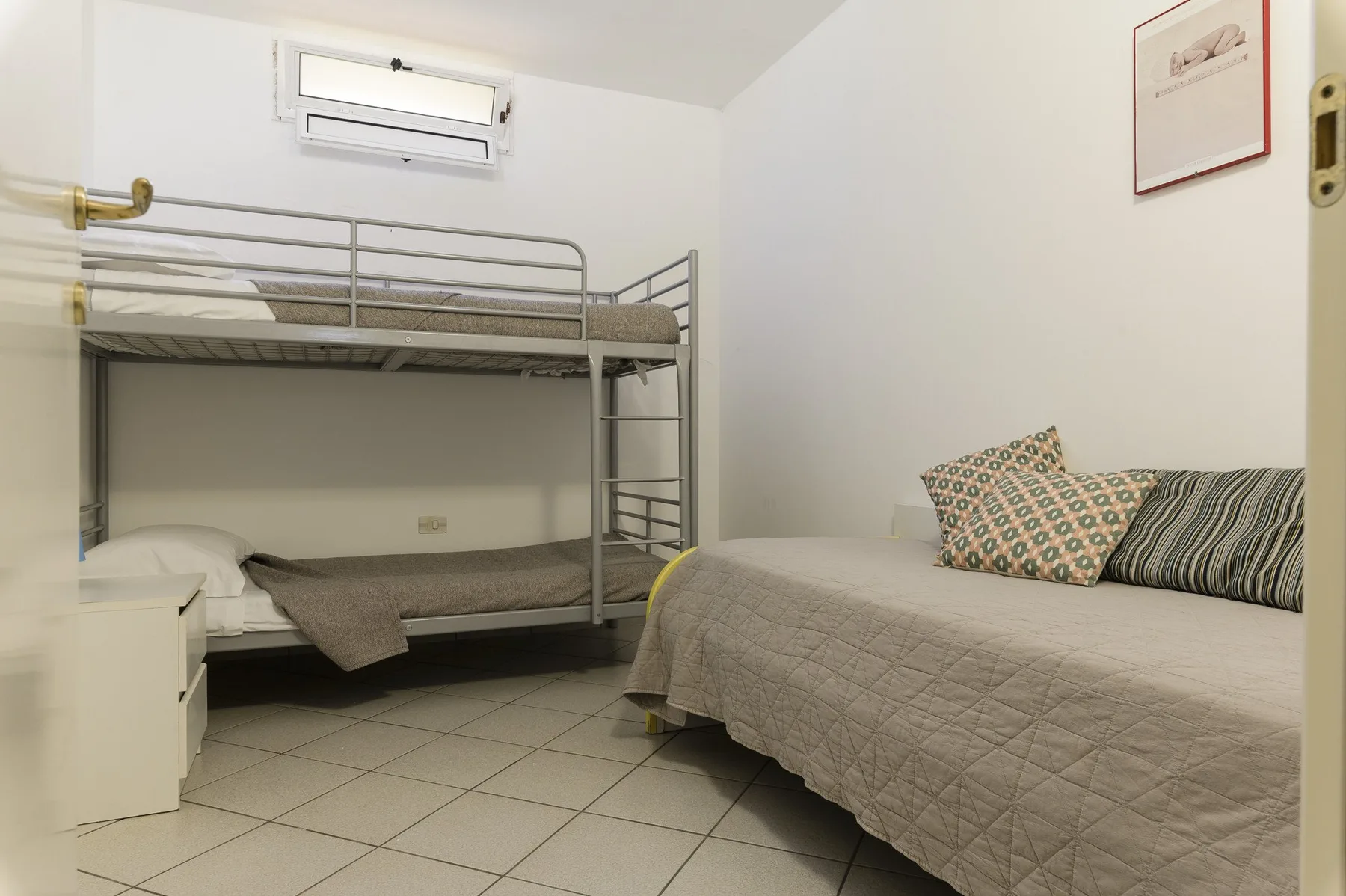 A bedroom with a bunk bed and a larger bed.