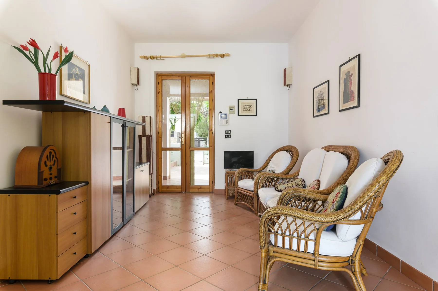 A bright sitting room with wicker seating and a glass-paneled door.
