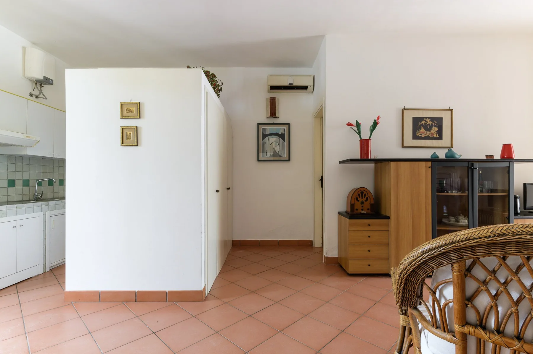 A tiled living area with wooden cabinets and a woven chair.