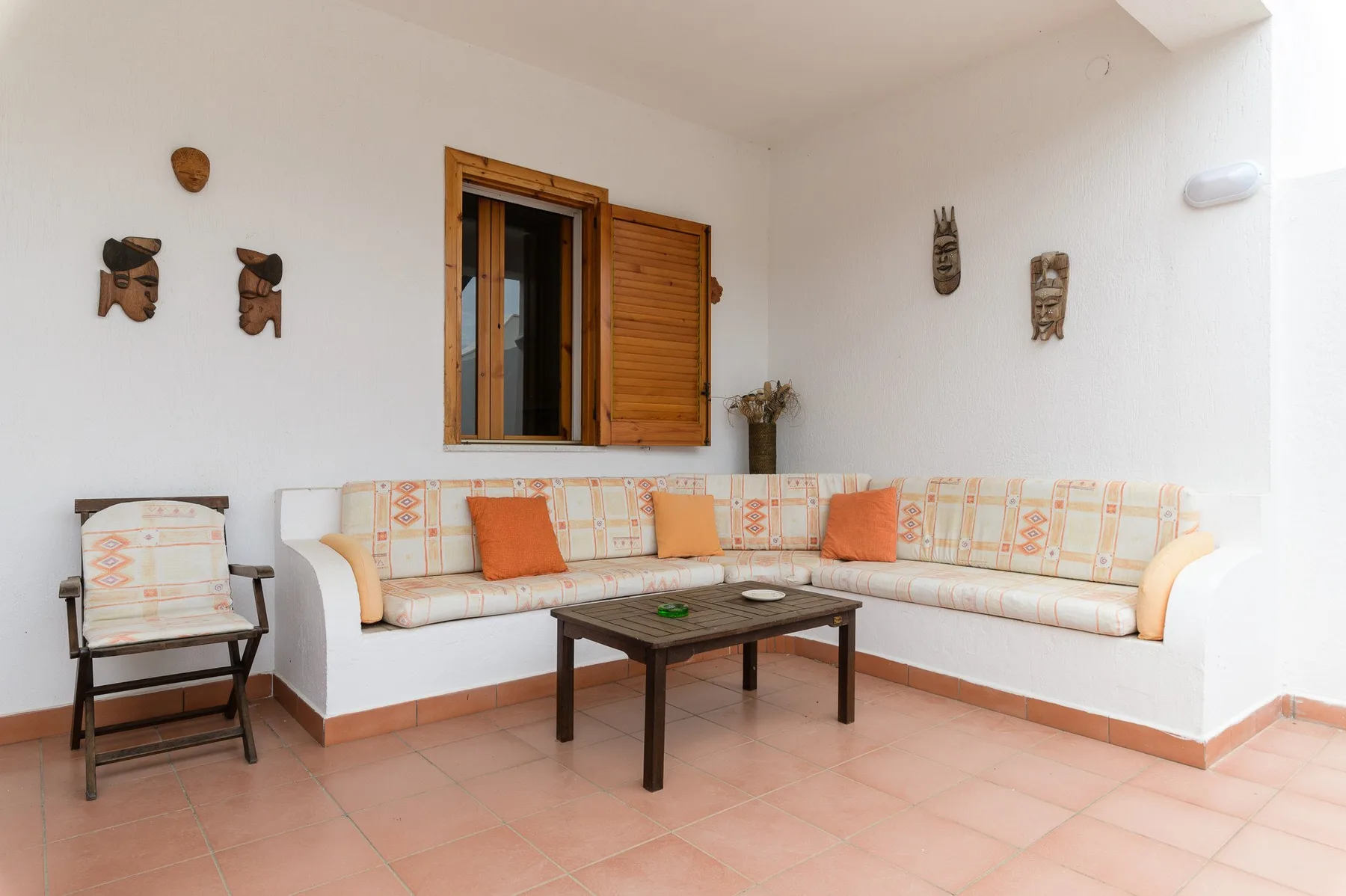 A bright covered patio with an L-shaped seating area and a low table.