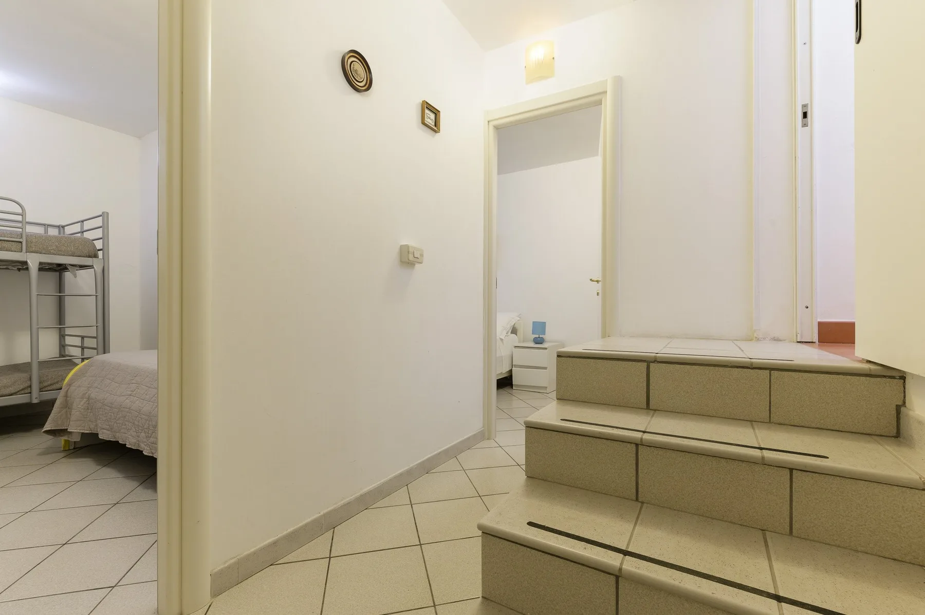 A tiled interior hallway leads to a doorway beside a short flight of steps.