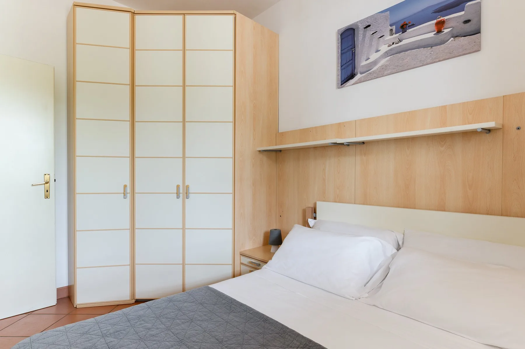 A bedroom with a bed and a large wardrobe.