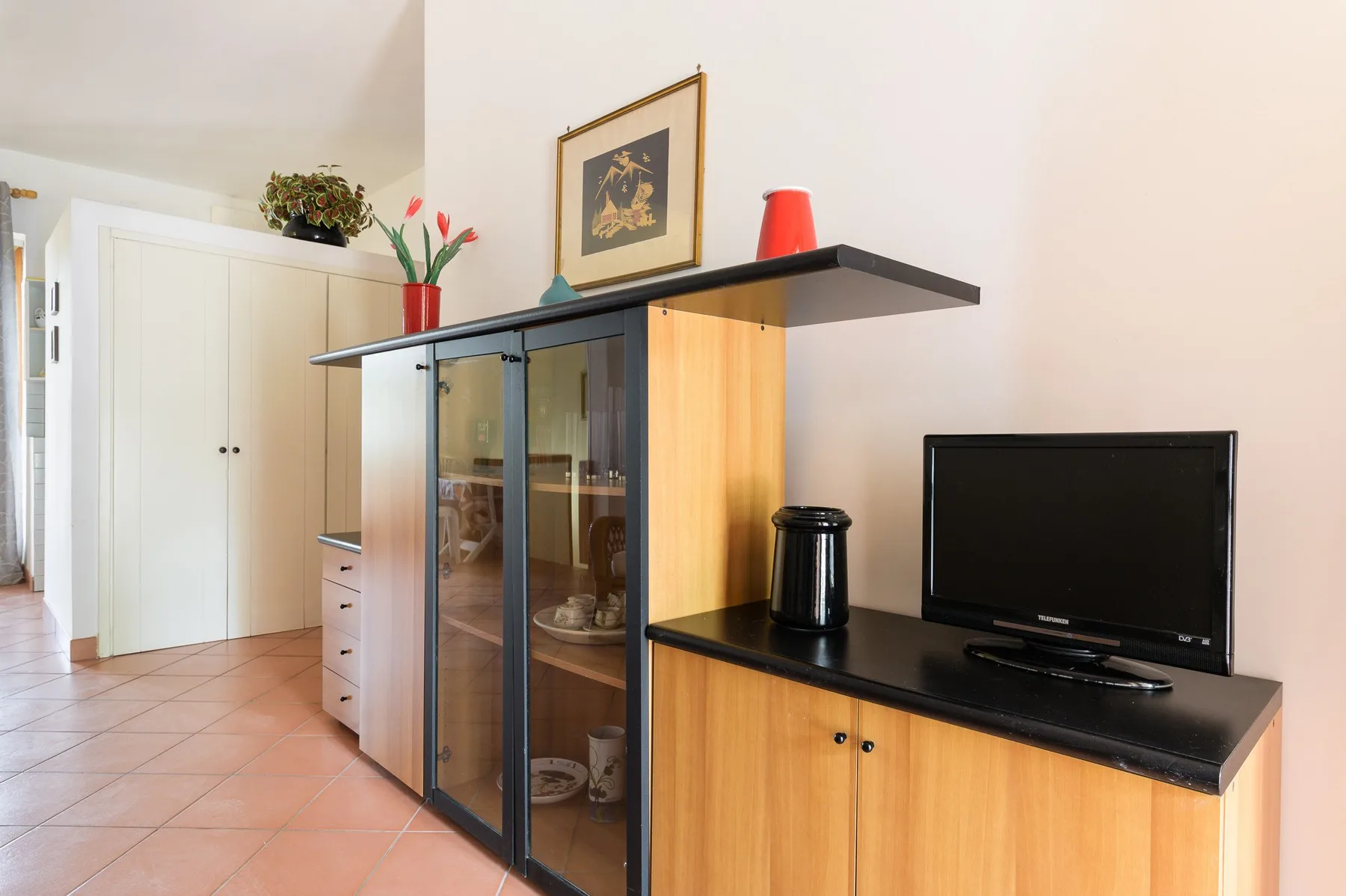 A living room with a television beside a glass-fronted display cabinet.