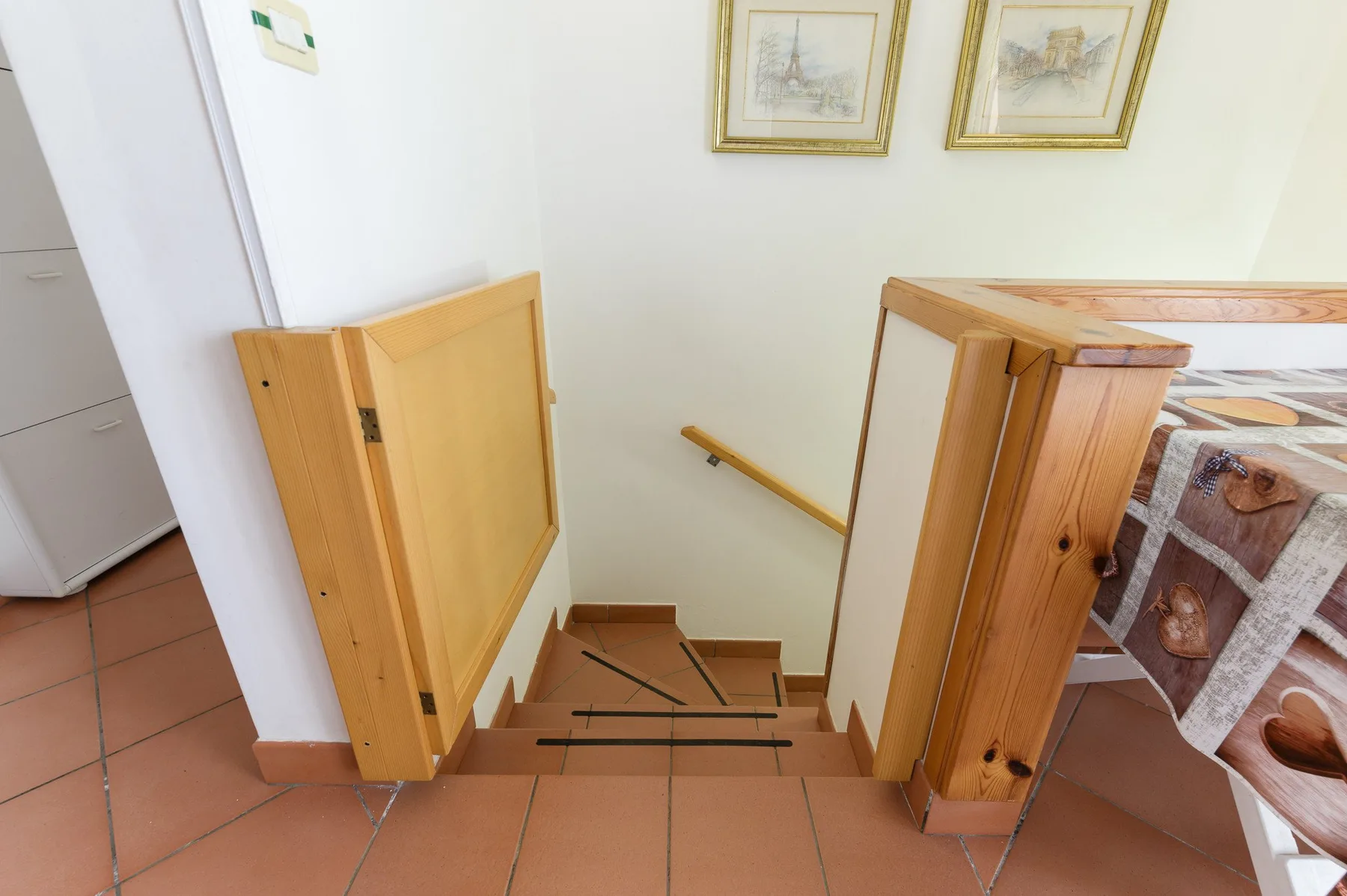 A tiled landing overlooks a staircase with wooden railings.