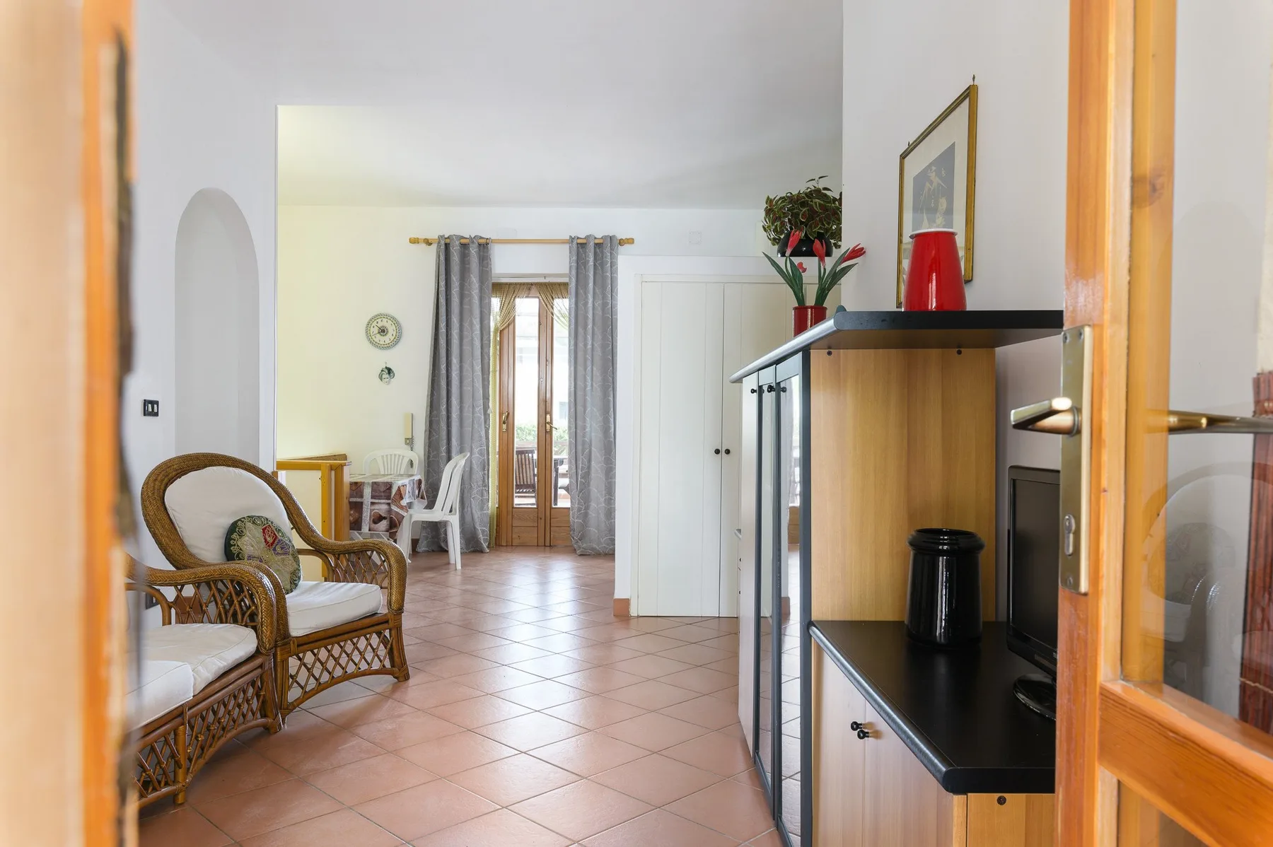 A living room with wicker seating and a tiled floor.