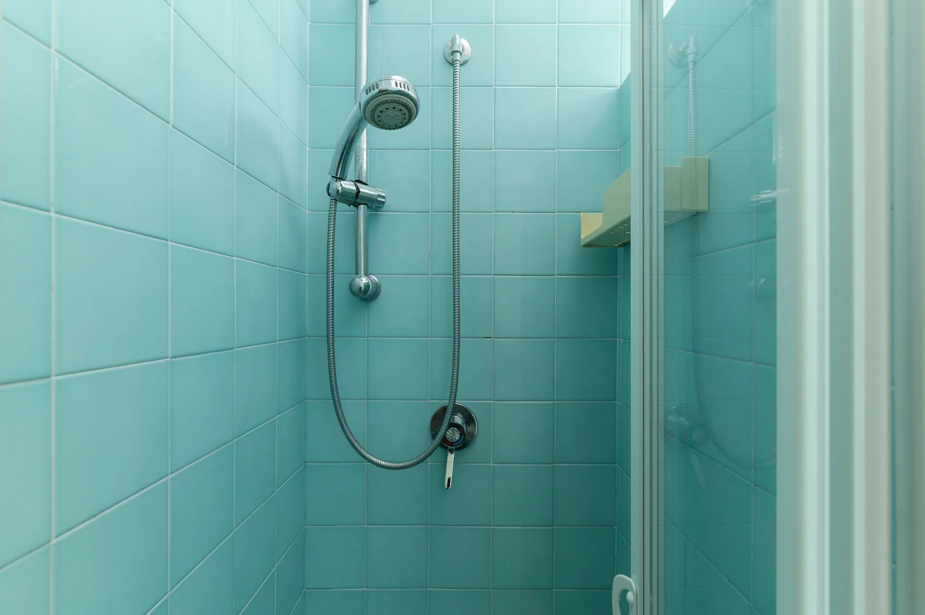 A tiled shower with a handheld showerhead and glass enclosure.