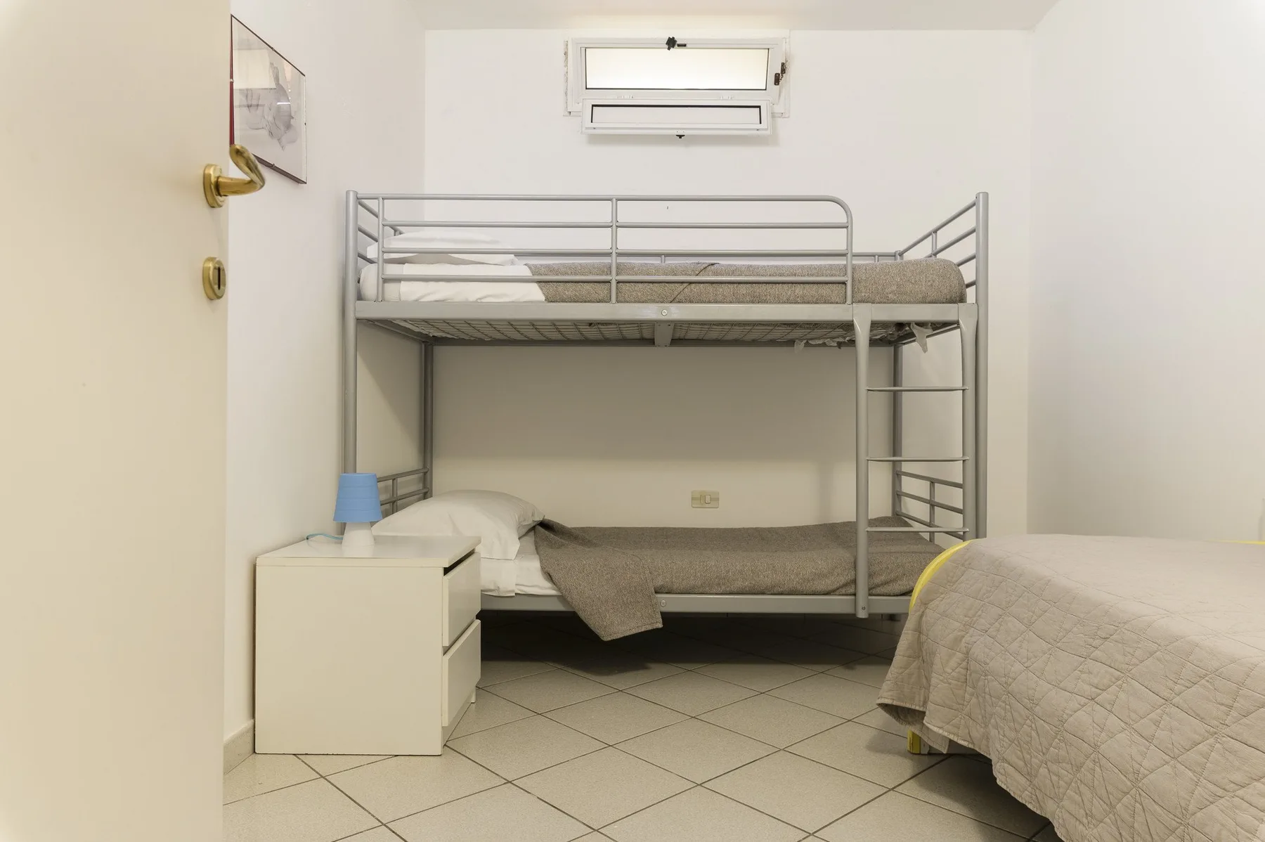 A bedroom with a metal bunk bed and a separate bed.