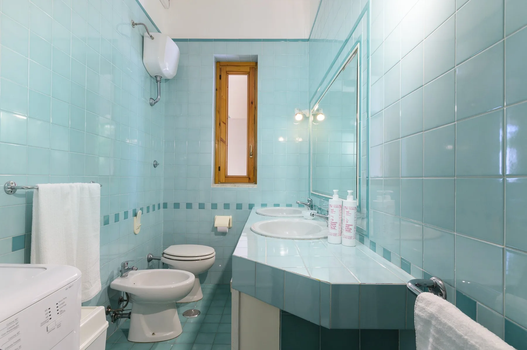 A tiled bathroom with a sink, toilet, and large vanity mirror.