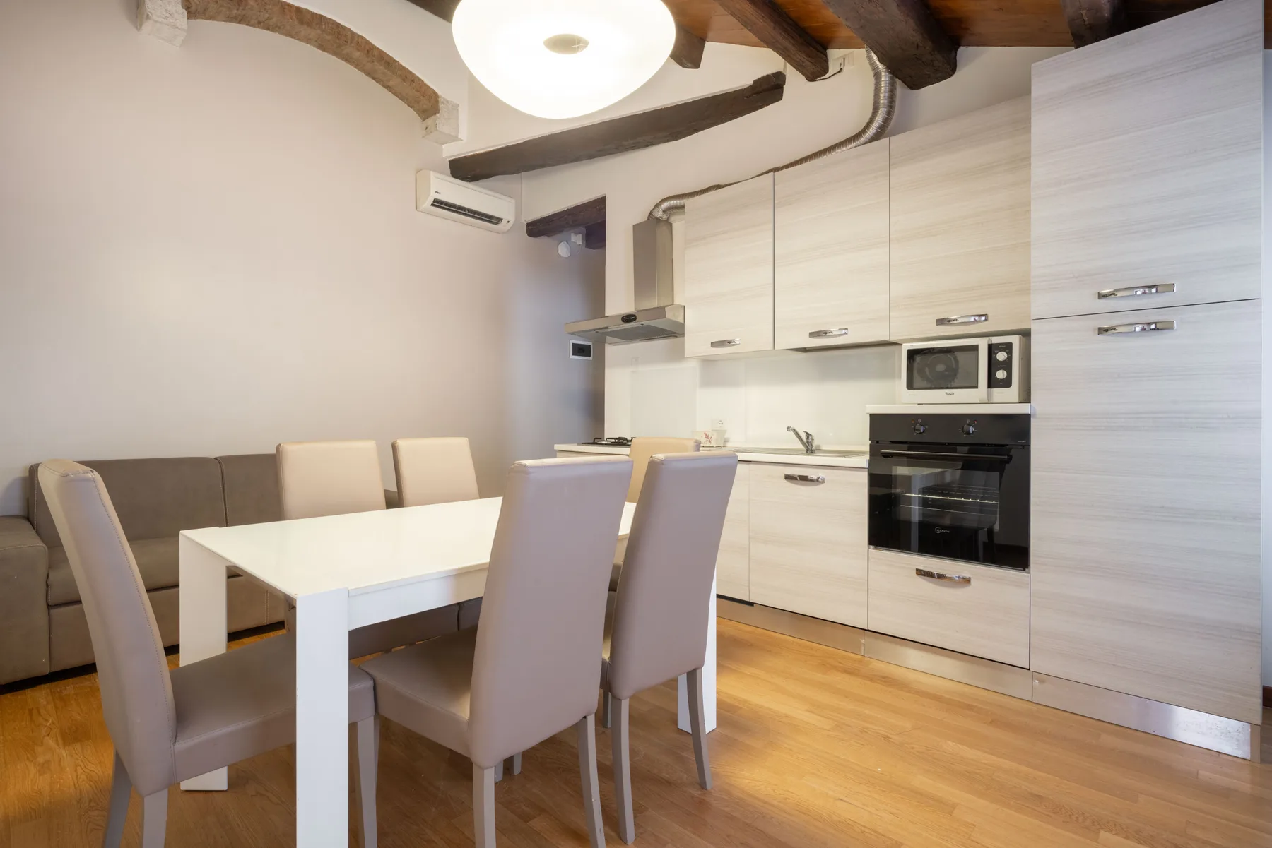 Un comedor con una mesa y asientos junto a una cocina moderna.