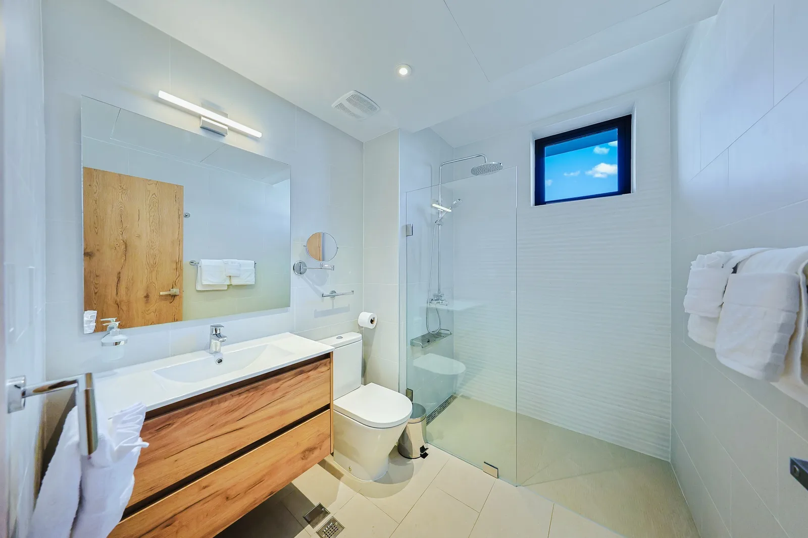 Step into your modern, spa-inspired bathroom with a sleek glass-enclosed shower and warm wood accents