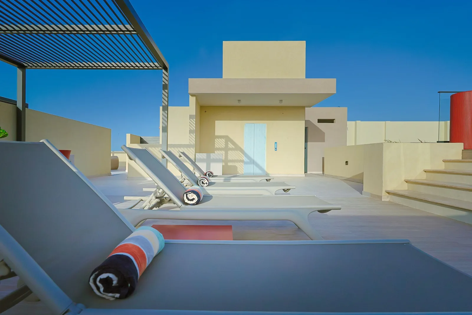 Spacious rooftop terrace with sun loungers and modern architecture invites you to soak up the island sun in style.