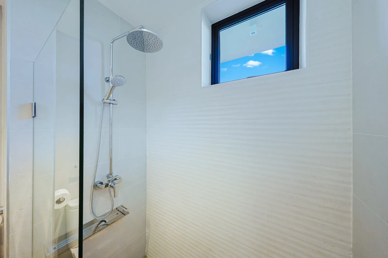 Step into your private sanctuary with a modern rainfall shower, dual showerheads, and natural light