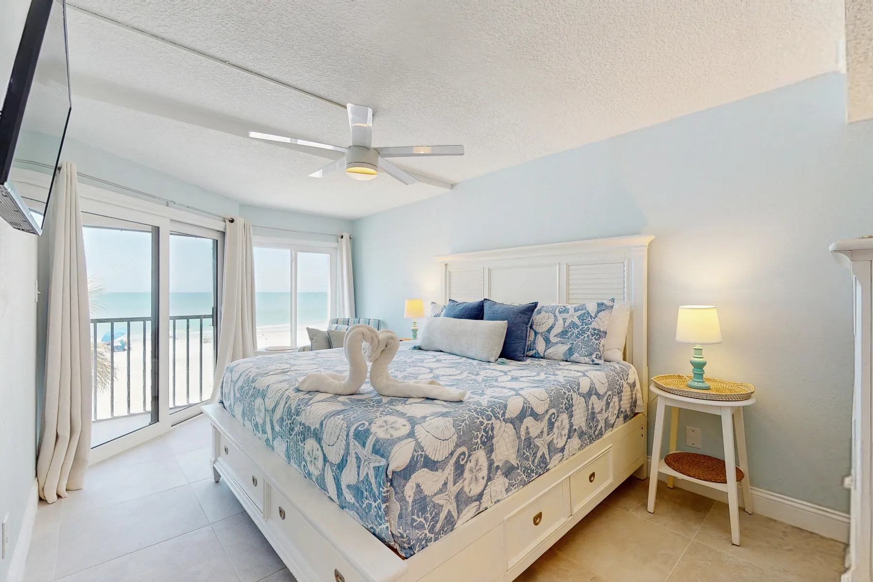 A bright bedroom with a bed beside glass doors opening to a balcony.