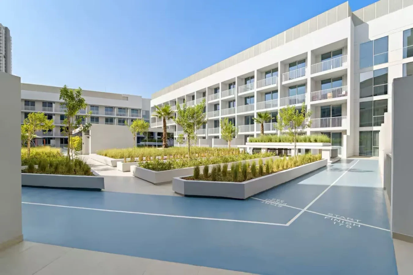 Un edificio moderno rodea un patio ajardinado con parterres.