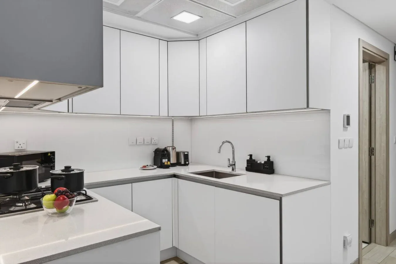 Una cocina blanca moderna con encimera en L, fregadero y estufa.