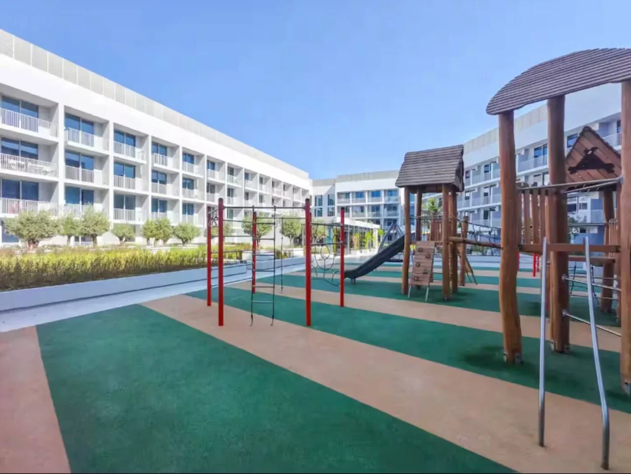 Un parque infantil al aire libre con estructuras para trepar y suelo verde.
