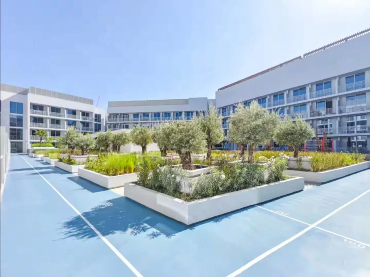 Un patio ajardinado con parterres elevados se encuentra entre edificios modernos.