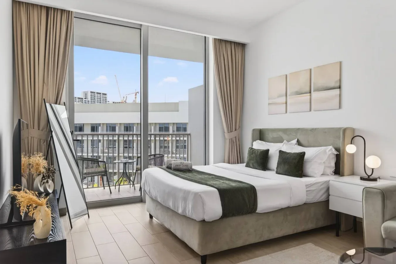 Un dormitorio con una cama bien arreglada y puertas de vidrio que dan a un balcón.
