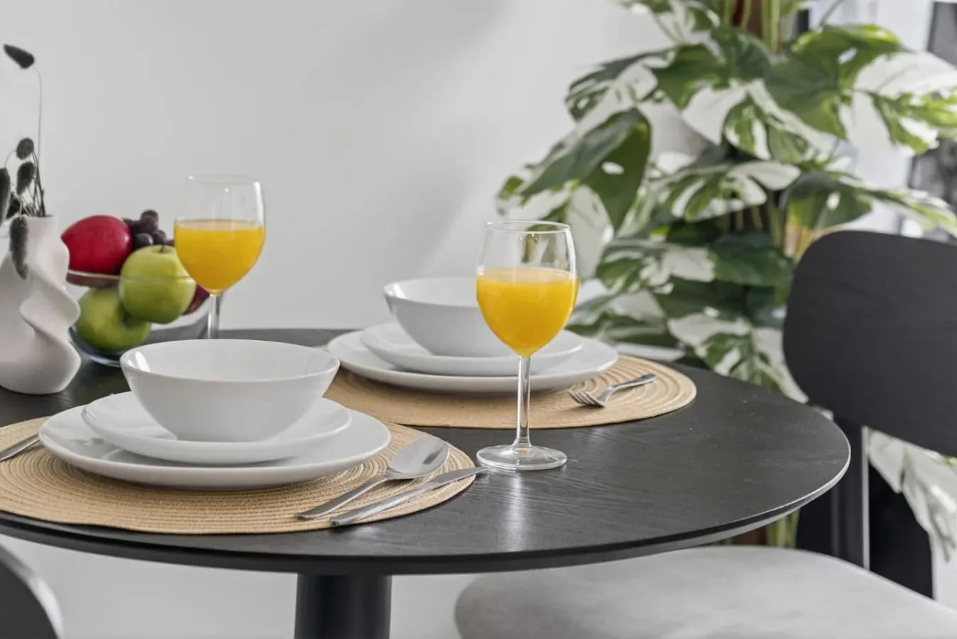Una mesa de comedor está puesta con cuencos, platos y vasos de zumo de naranja.