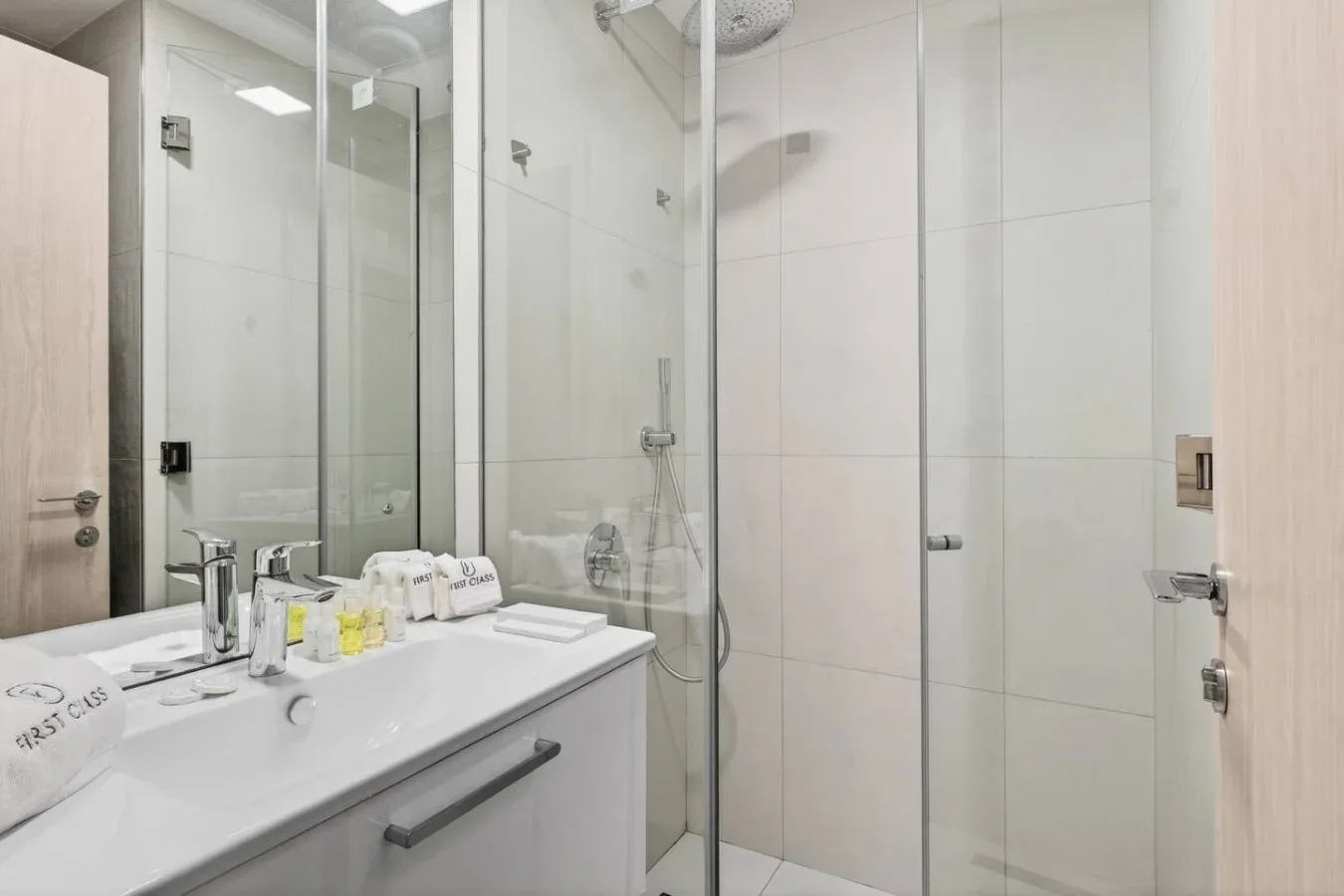 Un baño alicatado con lavabo y ducha de vidrio.