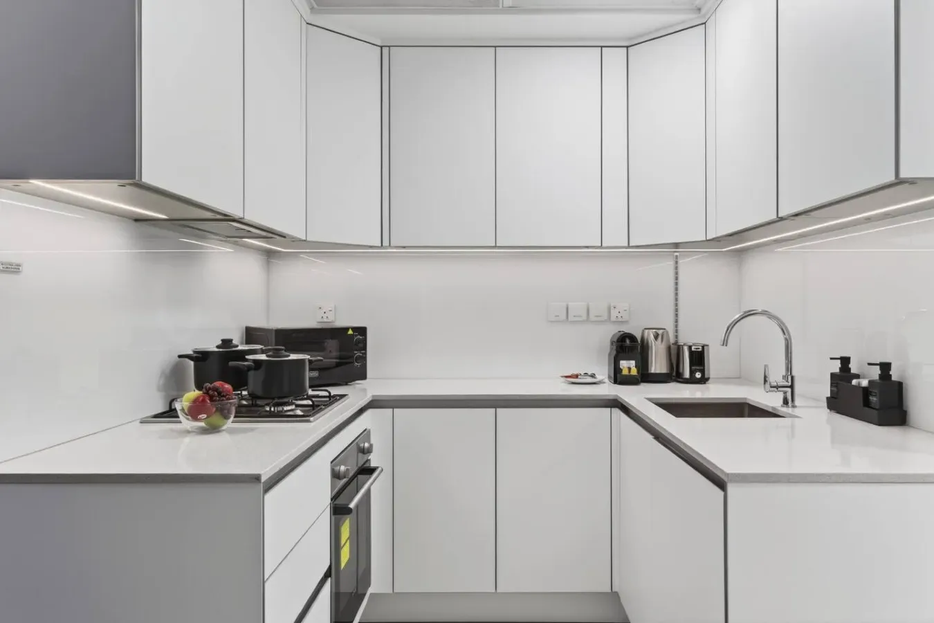 Una cocina moderna con gabinetes blancos, una placa de cocina y un fregadero.