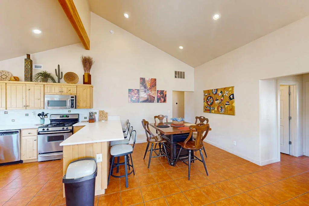 A kitchen and dining area with a counter, table, and wall art.