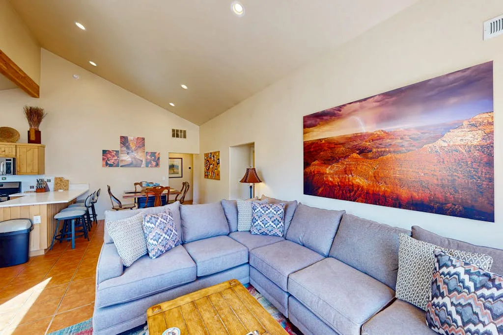 A living room with a large sectional sofa and colorful landscape artwork.