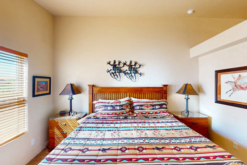 Bedroom with a bed covered in a colorful patterned quilt.