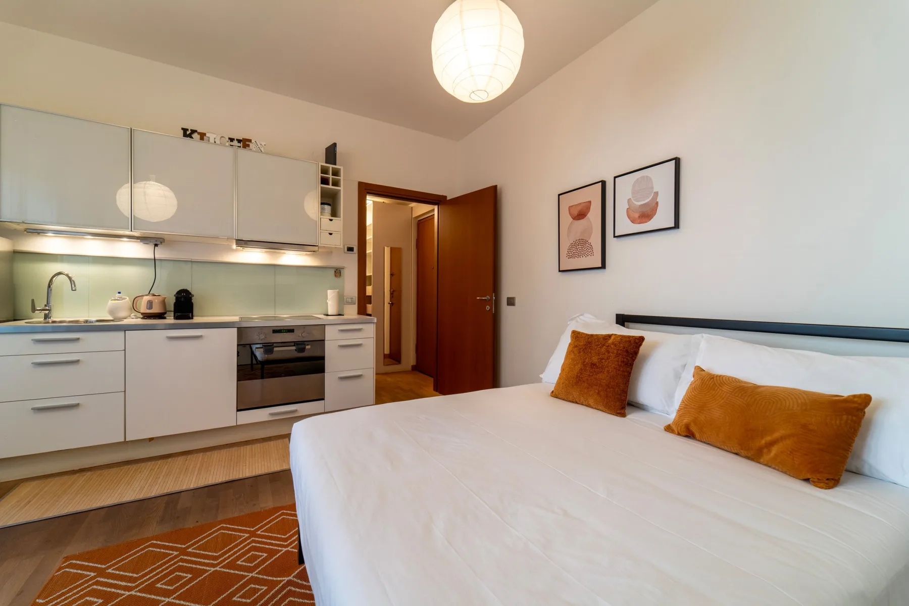 Un dormitorio con una cama grande junto a una pequeña cocina.