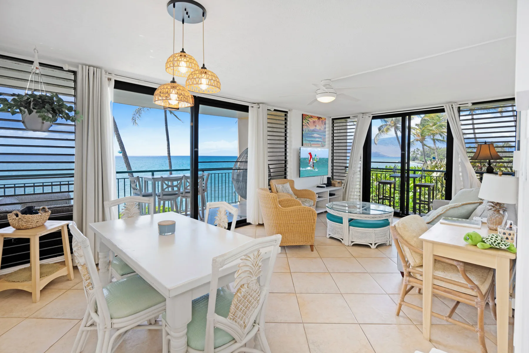 A bright living and dining area opens onto a balcony overlooking the ocean.