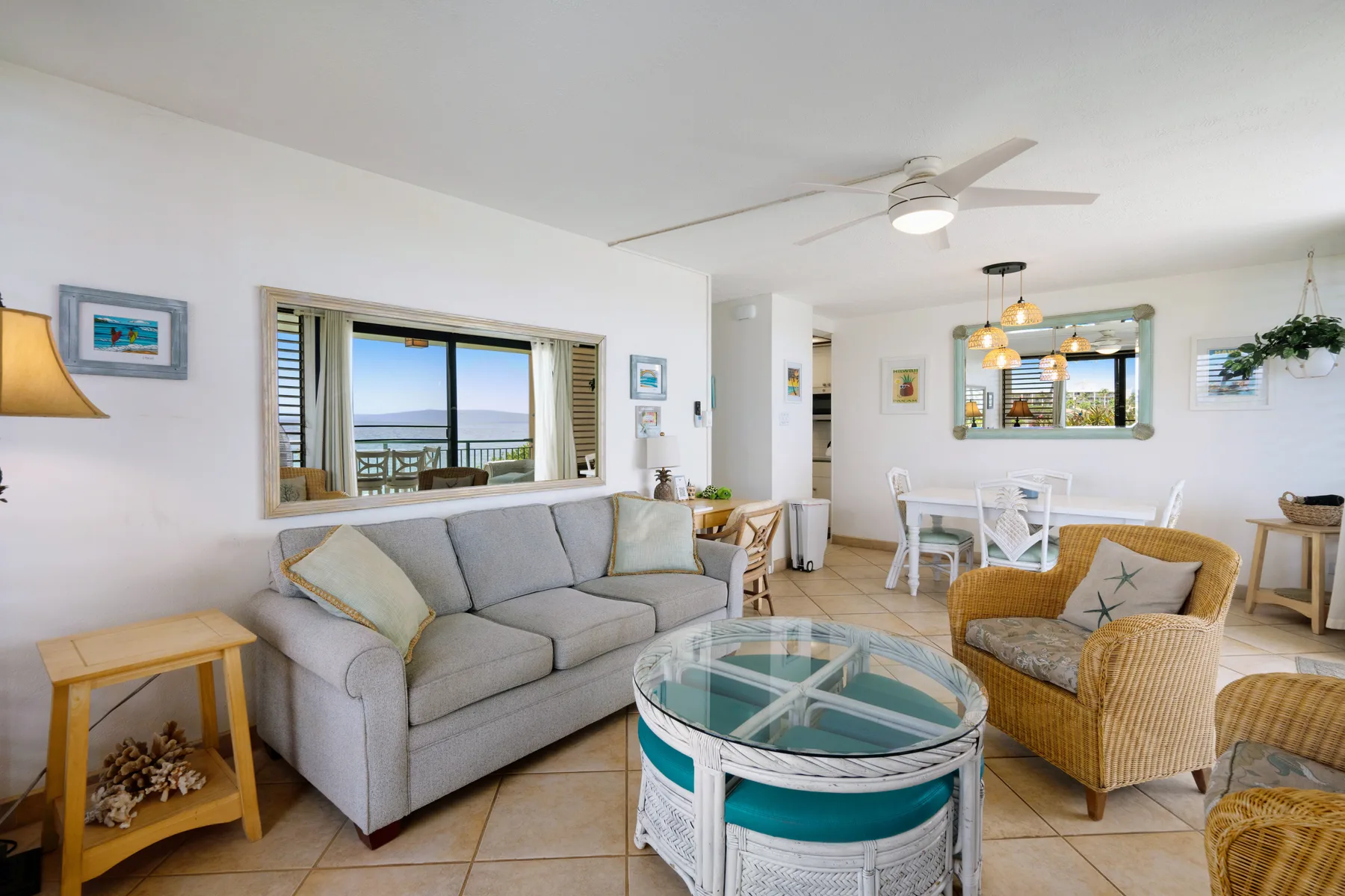 A bright living room with a gray sofa, wicker seating, and a glass coffee table.
