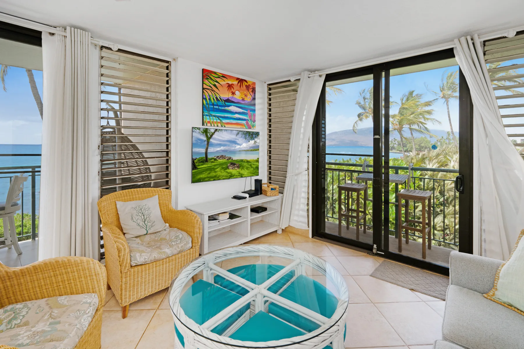 A bright living room opens onto a balcony with ocean views.