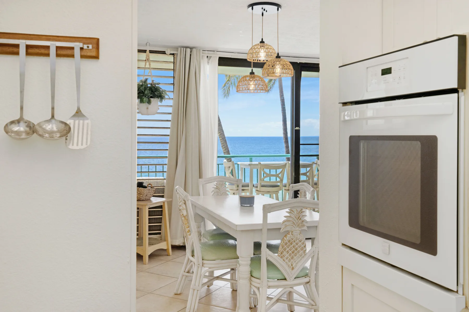 A dining area with a table and chairs beside windows overlooking the ocean.