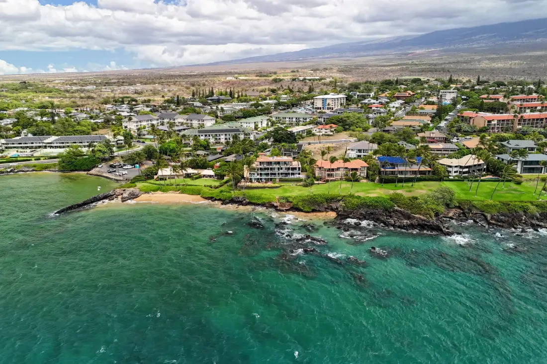 A coastal town sits along a rocky shoreline beside turquoise water.
