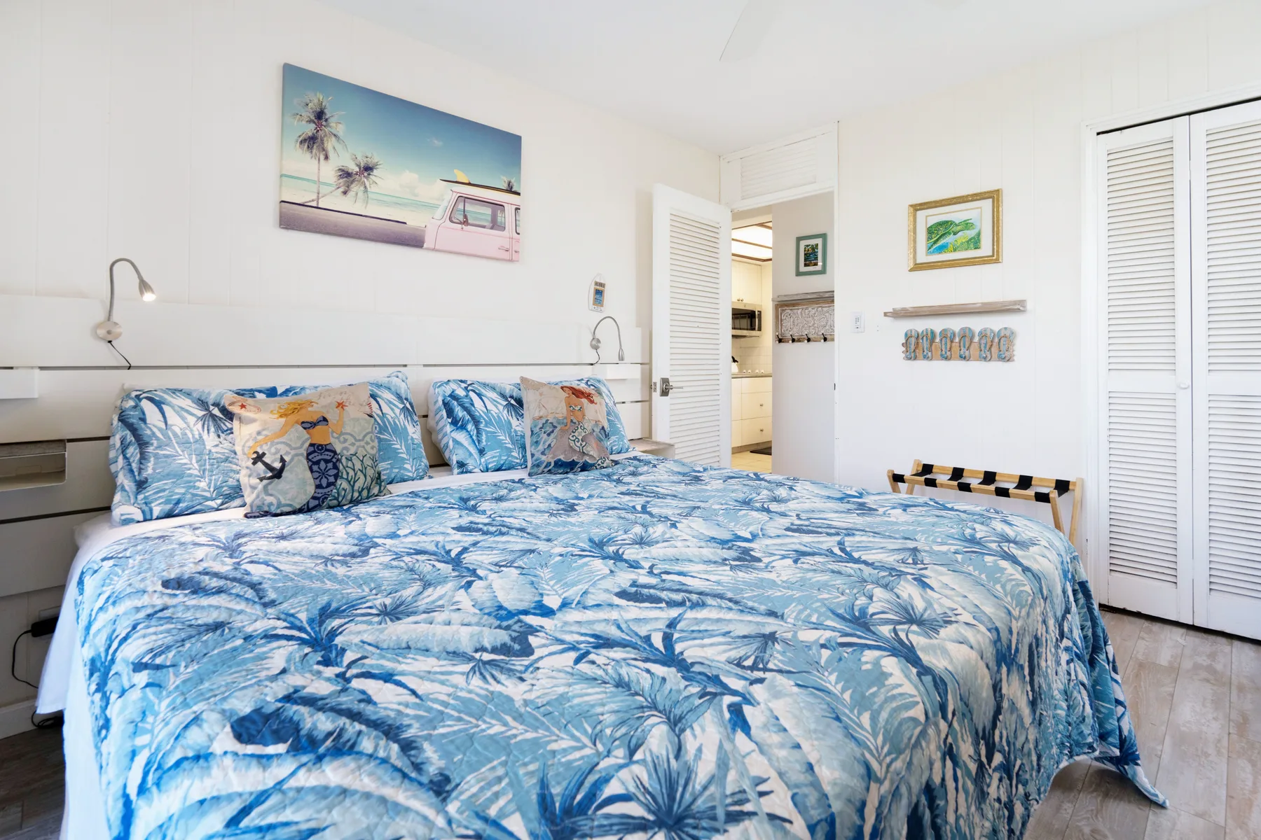 A bedroom with a bed covered in blue tropical-patterned bedding.