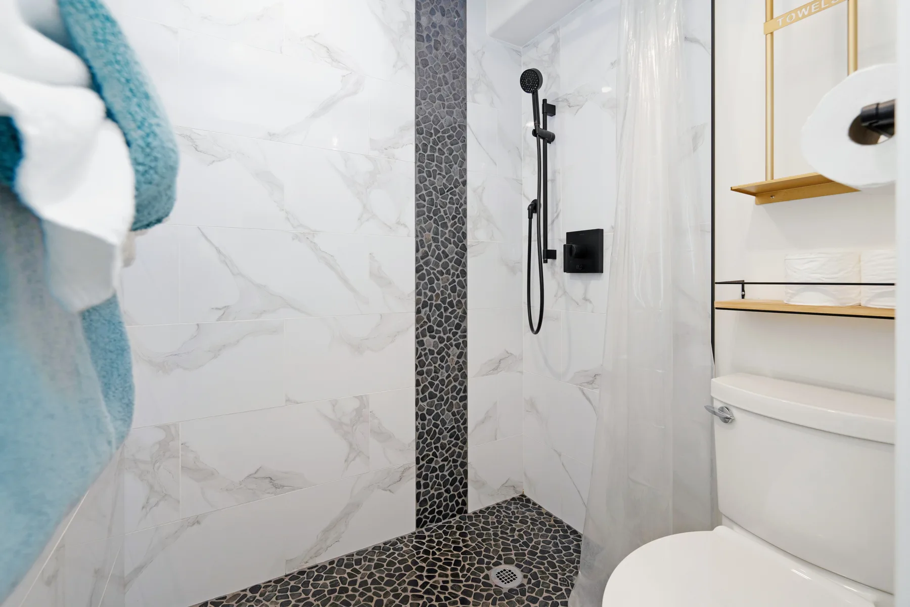 A bathroom with a walk-in shower, dark tiled floor, and toilet.