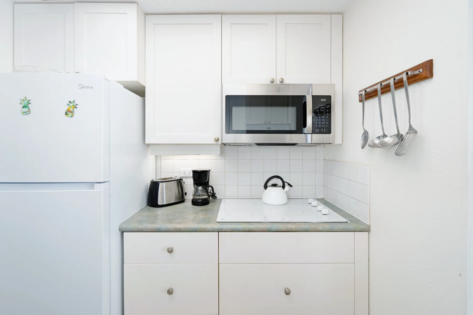 A compact kitchen with white cabinets and a countertop.