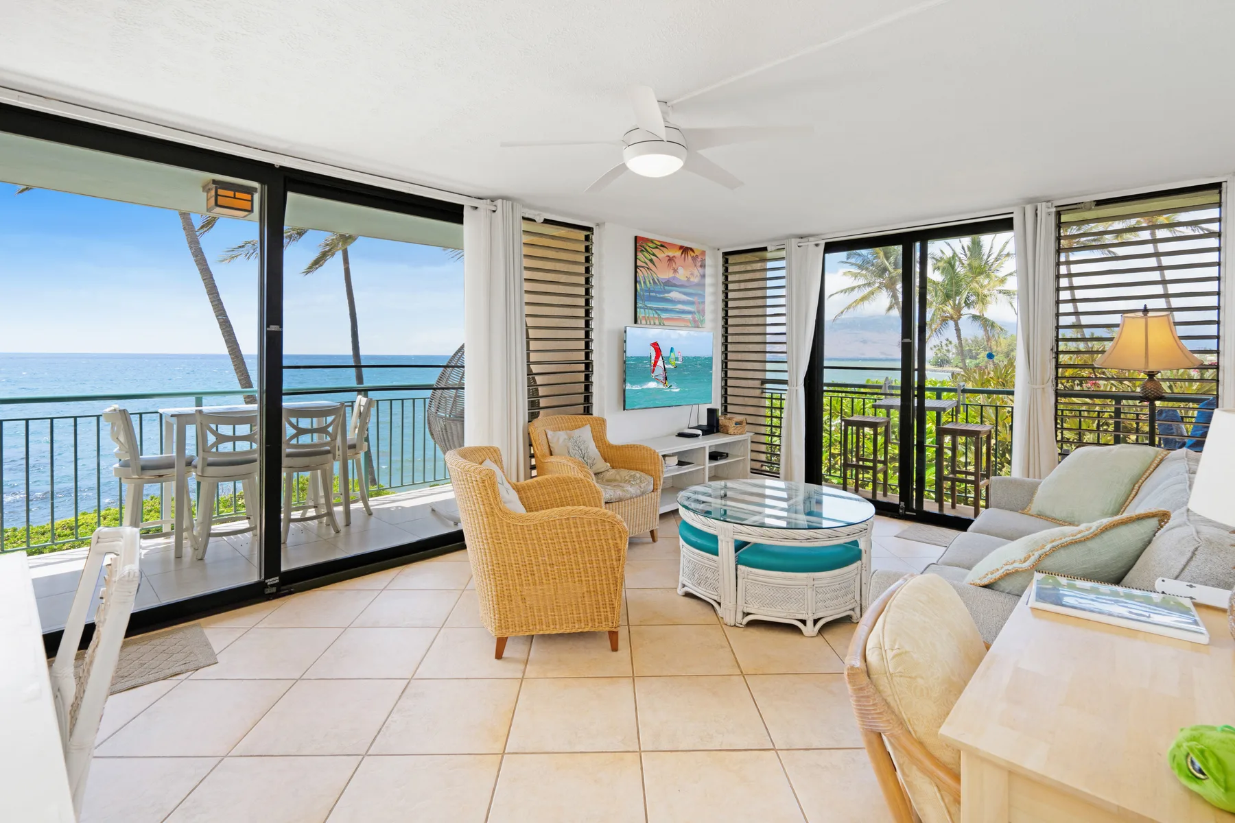 A bright living area opens onto a balcony overlooking the ocean.