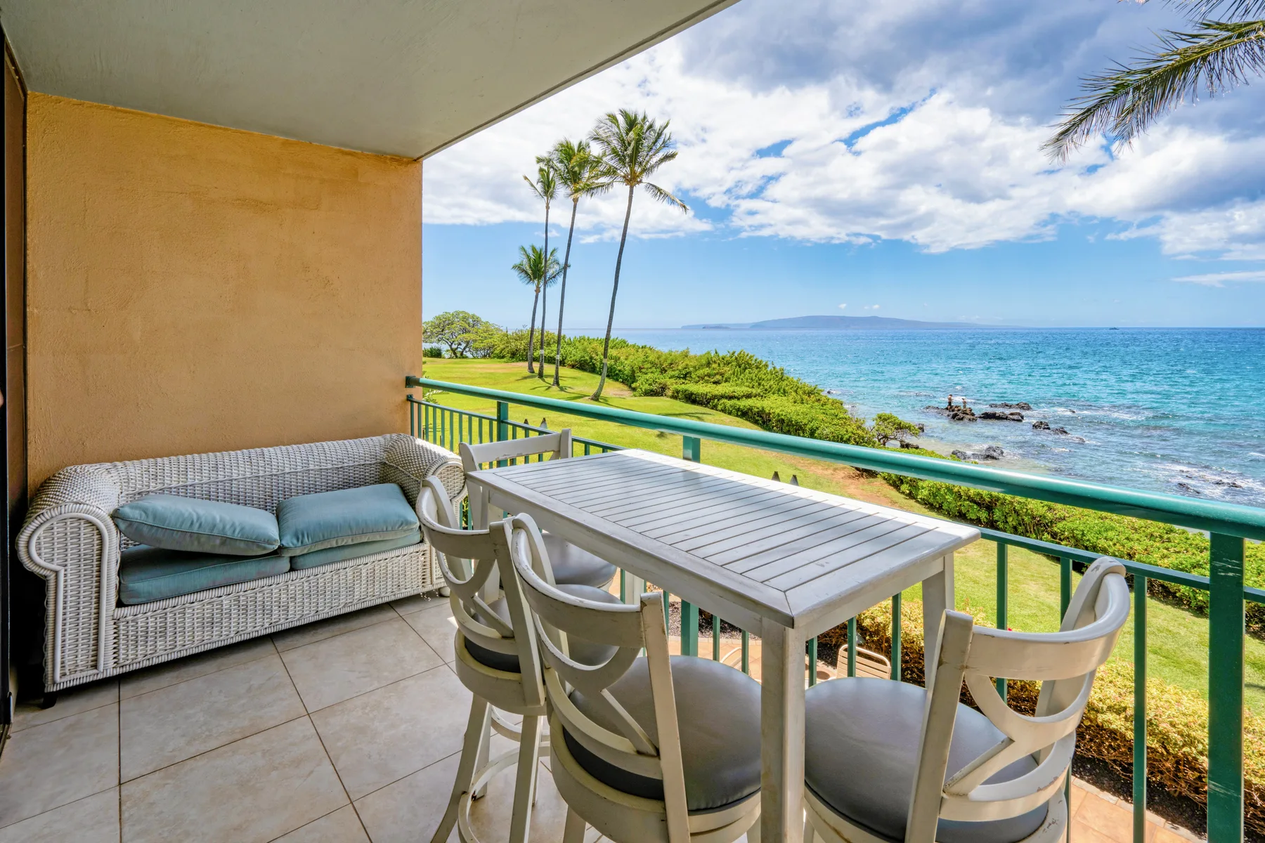 A seaside balcony has a dining table and seating overlooking the ocean.