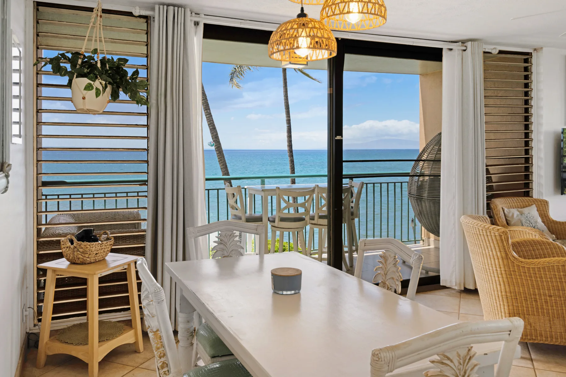 A bright dining area opens onto a balcony overlooking the ocean.